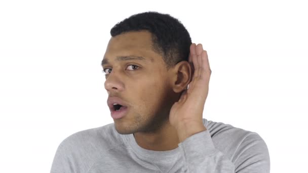 Młody przystojny mężczyzna afro-amerykański słuchania tajne, białe tło — Wideo stockowe