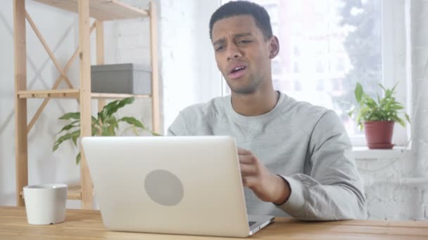 Homem afro-americano sentado no escritório perturbado por perda, trabalhando no laptop — Vídeo de Stock