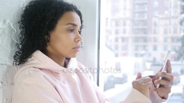 閲覧ウィンドウで座っているスマート フォン アフリカ系アメリカ人の女性 — ストック動画