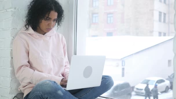 Femme afro-américaine pensant et travaillant, assise à la fenêtre — Video