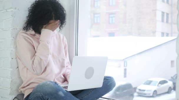 Tensión y dolor de cabeza, Mujer afroamericana frustrada con estrés, sentada en la ventana — Vídeo de stock