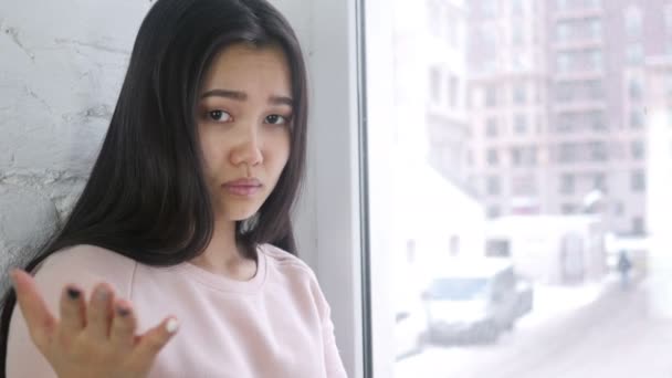 Jonge Aziatische vrouw in frustratie en woede, zitten ter venster — Stockvideo
