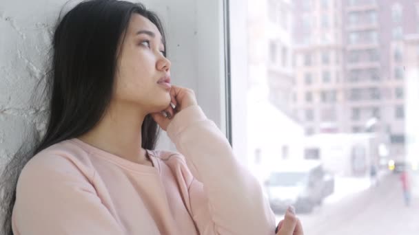Dalgın genç Asyalı kadın düşünme ve pencerede otururken beyin fırtınası — Stok video