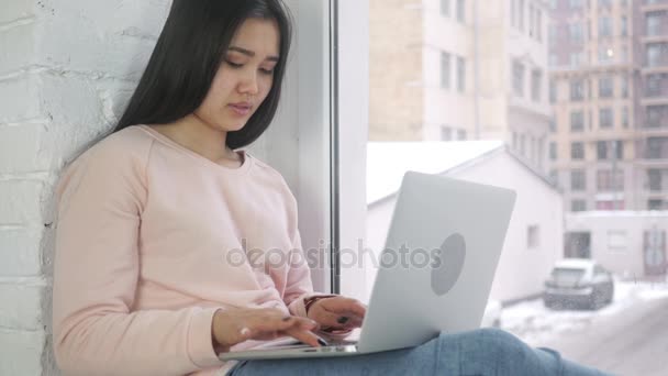 Захоплена афроамериканська жінка святкує успіх, працює на ноутбуці, сидить у вікні — стокове відео