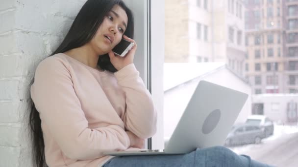 Jovem ásia mulher falando no telefone enquanto trabalhando no laptop — Vídeo de Stock