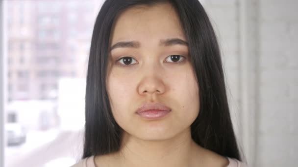 Primer plano de joven asiática mujer cara mirando cámara — Vídeos de Stock