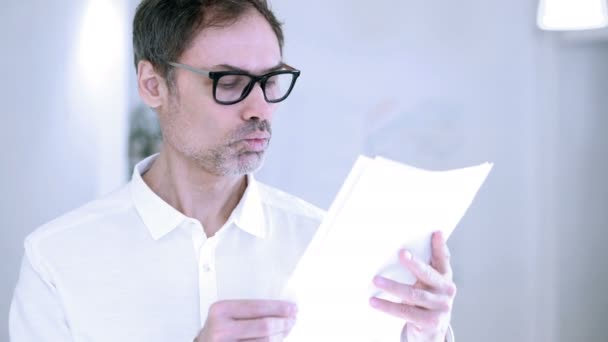 Hombre de mediana edad leyendo documentos en la oficina — Vídeos de Stock