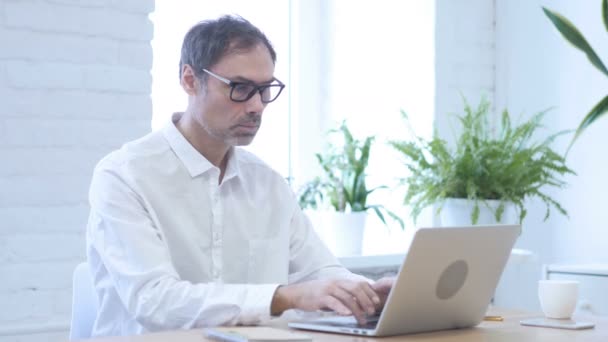 Ano, středního věku člověka přijetí nabídky třes hlavy při práci na notebooku — Stock video