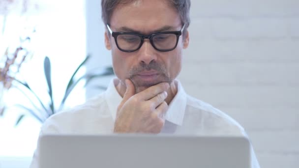 Nachdenklicher Mann mittleren Alters, der am Laptop denkt und arbeitet, Nahaufnahme — Stockvideo