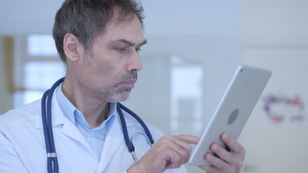 Врач печатает электронную почту на планшете, помогает пациентам — стоковое видео