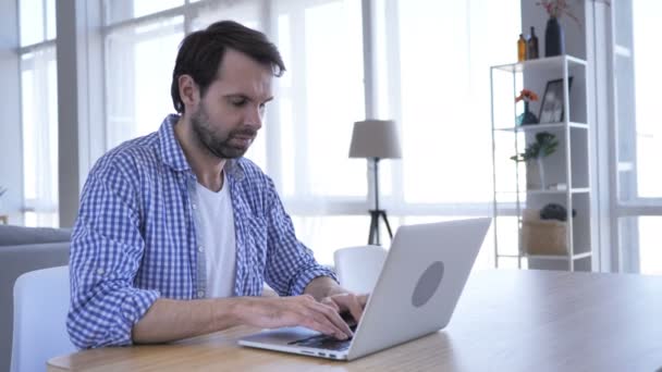 Mann steht unter Schock und fragt sich, während er am Laptop arbeitet — Stockvideo