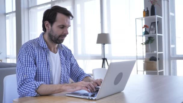 Mannen leende medan du tittar på kameran på jobbet, att skriva på Laptop — Stockvideo