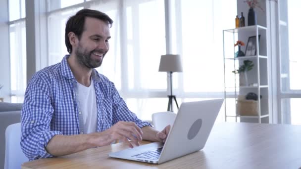 Chat de vídeo en línea en el ordenador portátil en el trabajo por el hombre de la barba casual — Vídeo de stock