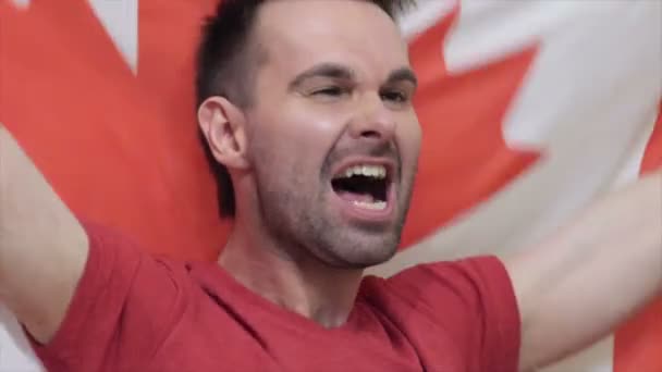 Kanadischer Fan feiert, während er die Fahne Kanadas in Zeitlupe hält — Stockvideo