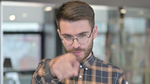 Retrato de un joven diseñador señalando con el dedo e invitando — Vídeos de Stock