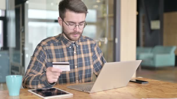 Επαγγελματίας νεαρός σχεδιαστής χρησιμοποιώντας πιστωτική κάρτα στο laptop — Αρχείο Βίντεο