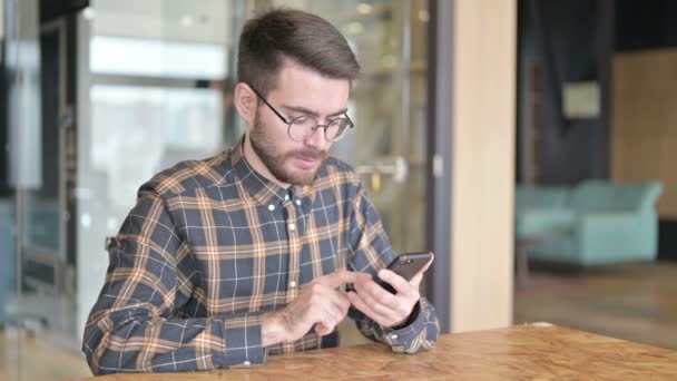 Młody projektant odniósł sukces na smartfonie w biurze — Wideo stockowe