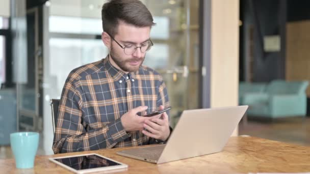 Aantrekkelijke jonge ontwerper in gesprek op Smartphone in Office — Stockvideo