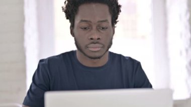 Dizüstü bilgisayarda çalışan ve ofiste öksüren hasta Afrikalı adam.