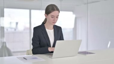 Ofiste dizüstü bilgisayar üzerinde çalışan ciddi genç iş kadını