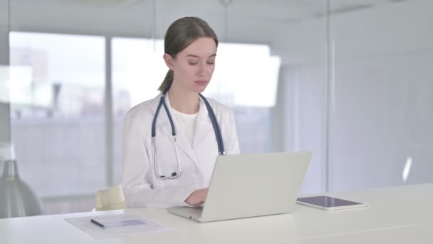 Веселая молодая женщина-врач работает на ноутбуке в офисе — стоковое видео