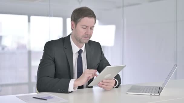 Tvrdě pracující středověký podnikatel používající tablet v kanceláři — Stock video
