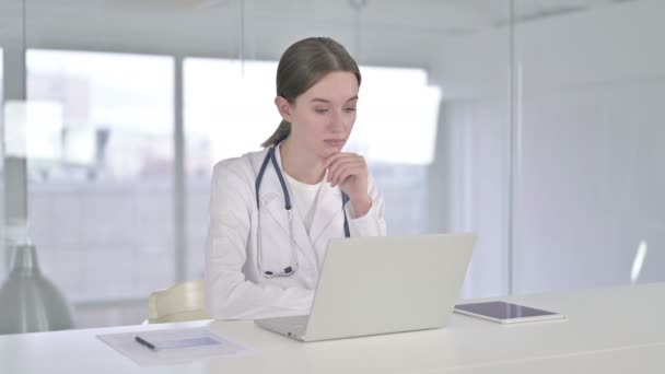 Ung kvinnlig doktor tänker och arbetar på laptop i Office — Stockvideo