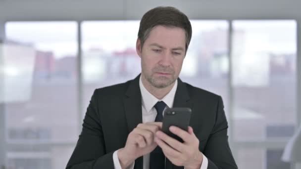 Vidám középkorú üzletember Ünnepeljen okostelefonon — Stock videók