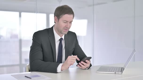 Empresario de mediana edad celebrando el éxito en el teléfono inteligente — Vídeo de stock