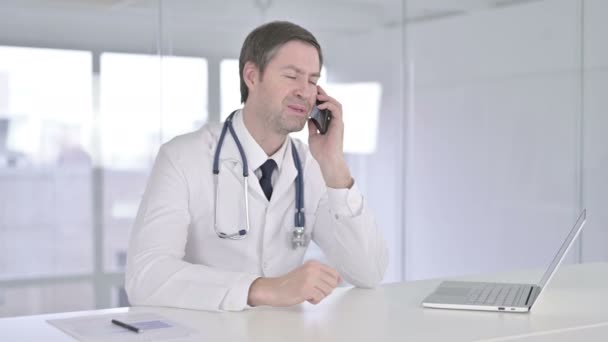 Feliz médico de mediana edad hablando por teléfono inteligente — Vídeos de Stock