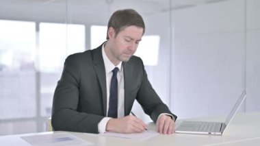 Ofiste evrak işi yapan ciddi bir orta yaşlı işadamı. 