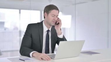 Orta Çağ İşadamı Akıllı Telefonla Konuşuyor ve Bilgisayarda Çalışıyor