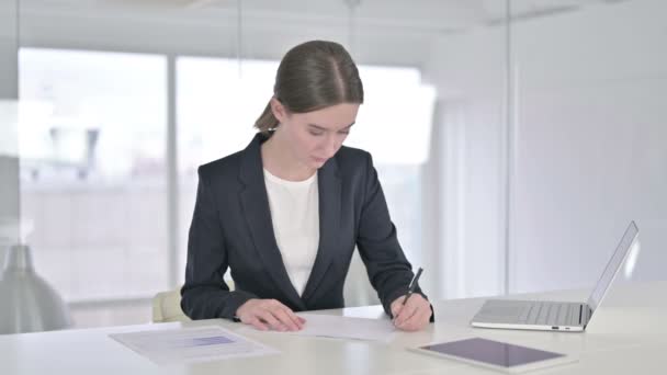 Joven empresaria enfocada a escribir sobre papel en la oficina moderna — Vídeos de Stock