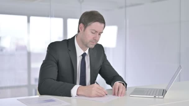 Разочарованный бизнесмен среднего возраста пытается писать на бумаге — стоковое видео