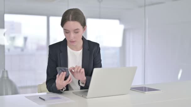Aantrekkelijke jonge zakenvrouw met Smartphone op kantoor — Stockvideo
