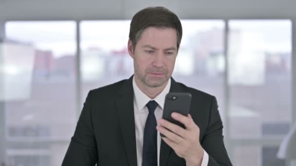 Middeleeuws zakenman geschokt met behulp van Smartphone in Office — Stockvideo