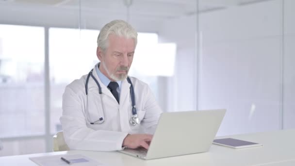Fokuserad äldre läkare som arbetar på laptop — Stockvideo