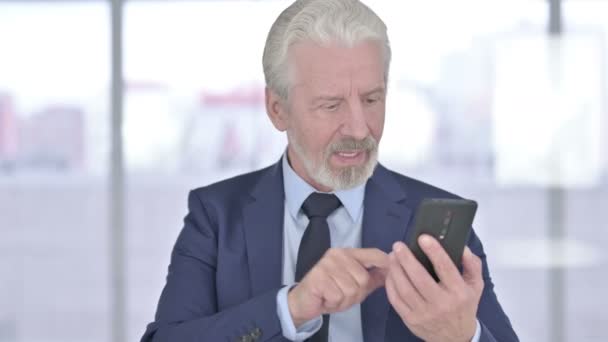 スマートフォンで成功を祝う高齢ビジネスマンの肖像 — ストック動画