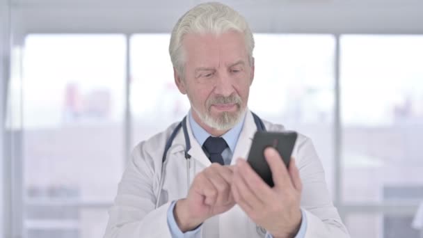 Portret van Vrolijke Senior Old Doctor met behulp van Smartphone in Office — Stockvideo