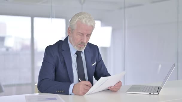 Geschäftsmann mittleren Alters liest Dokumente im Büro — Stockvideo