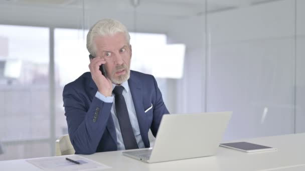 Счастливый бизнесмен среднего возраста разговаривает по смартфону в офисе — стоковое видео