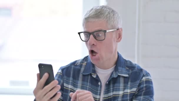 Retrato del hombre de mediana edad casual reaccionando al fracaso en el teléfono inteligente — Vídeos de Stock