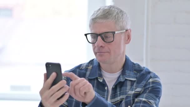 Retrato del hombre de mediana edad casual celebrando el éxito en el teléfono inteligente — Vídeos de Stock