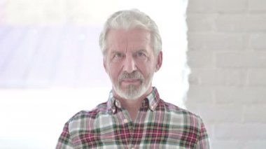 Sıradan yaşlı adam kameraya el sallıyor. Merhaba.