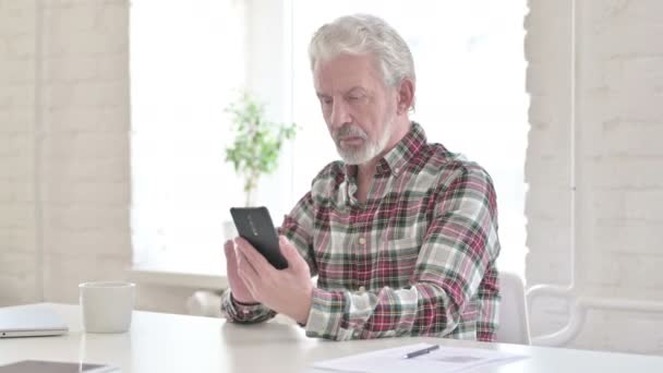 現代オフィスでスマートフォンを使用してフォーカスシニア男性デザイナー — ストック動画