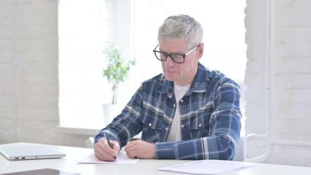 Serieuze toevallige middelbare leeftijd man doet papierwerk — Stockvideo