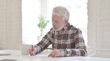 Ofiste evrak işi yapan ciddi bir ihtiyar. 