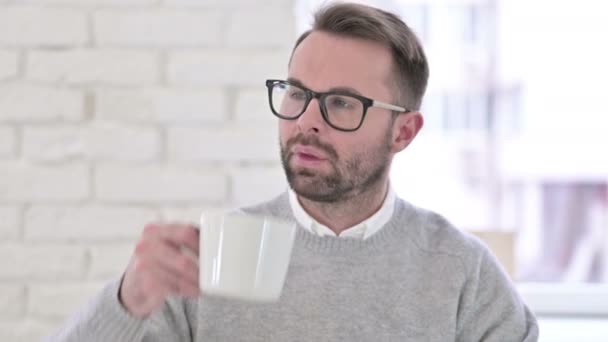 Jovem designer bebendo café no escritório moderno — Vídeo de Stock