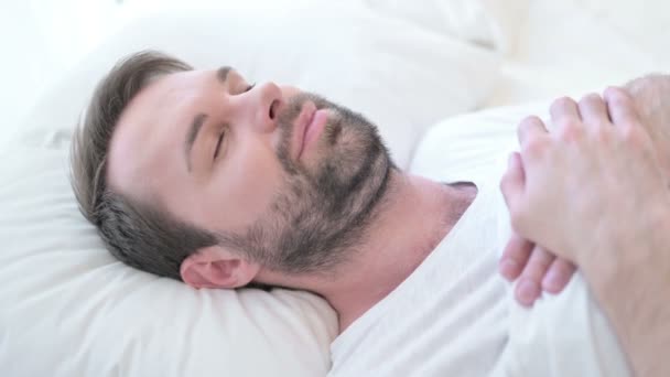 Aggódó szakállas fiatalember próbál aludni az ágyban — Stock videók