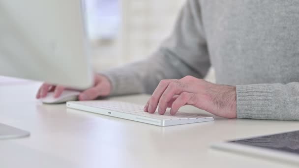 Чоловік набирає на клавіатурі, працює на комп'ютері — стокове відео